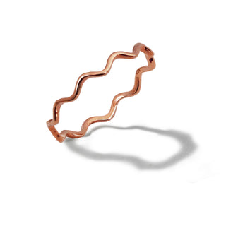 A delicate, wavy-patterned rose gold ring called the Noodle Ramen Ring by Sonia Hou Jewelry is displayed on a white background. The ring's wavy design, reminiscent of the artistry in Asian culture, casts a soft shadow that emphasizes its unique shape. The overall aesthetic is minimalistic and elegant, promising both beauty and longevity.